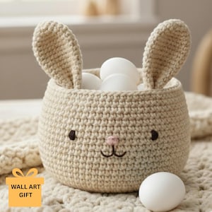 May include: A beige crochet bunny basket with two upright ears, black eyes, and a pink nose. The basket is filled with white eggs. The words "WALL ART GIFT" are on a yellow square in the lower left corner.