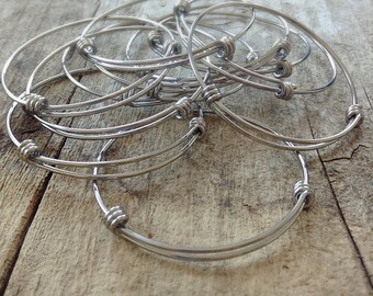 May include: A set of silver bangle bracelets with a knotted design. The bracelets are stacked on top of each other.
