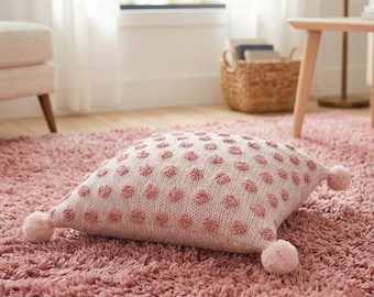 Pink decorative cushion with floral polka dots and pom-poms