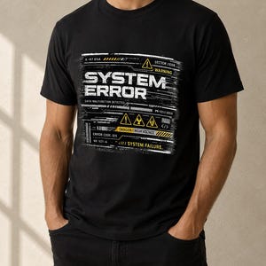 May include: A black short-sleeved t-shirt featuring a graphic print with the text SYSTEM ERROR, DATA MALFUNCTION DETECTED, DANGER HIGH VOLTAGE, and SYSTEM FAILURE. The design includes yellow warning icons and technical data in white and yellow.