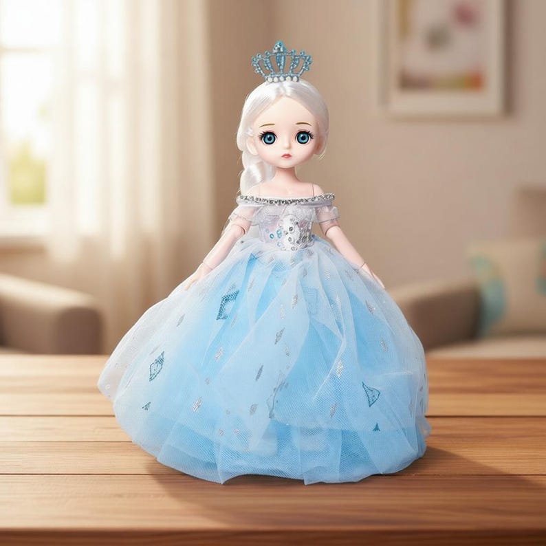 May include: A doll with white hair styled in a braid and a blue crown, wearing an off-the-shoulder dress with a bodice featuring blue and silver accents and a layered, light blue tulle skirt decorated with small, scattered silver diamond shapes.