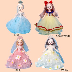 May include: Four dolls dressed in elaborate gowns and crowns. The top left doll, labeled Elsa, wears a blue dress. The top right doll, labeled Snow White, wears a yellow dress with a red bow. The bottom left doll, labeled Pink, wears a pink dress. The bottom right doll, labeled White, wears a white dress.