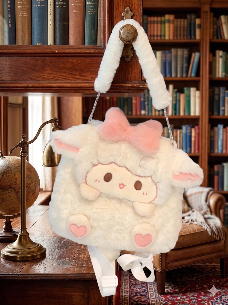 May include: A cream-coloured sheep-shaped handbag with a pink bow and heart details. The bag has a cartoon sheep face and a white strap. The bag is suspended from a wooden door.