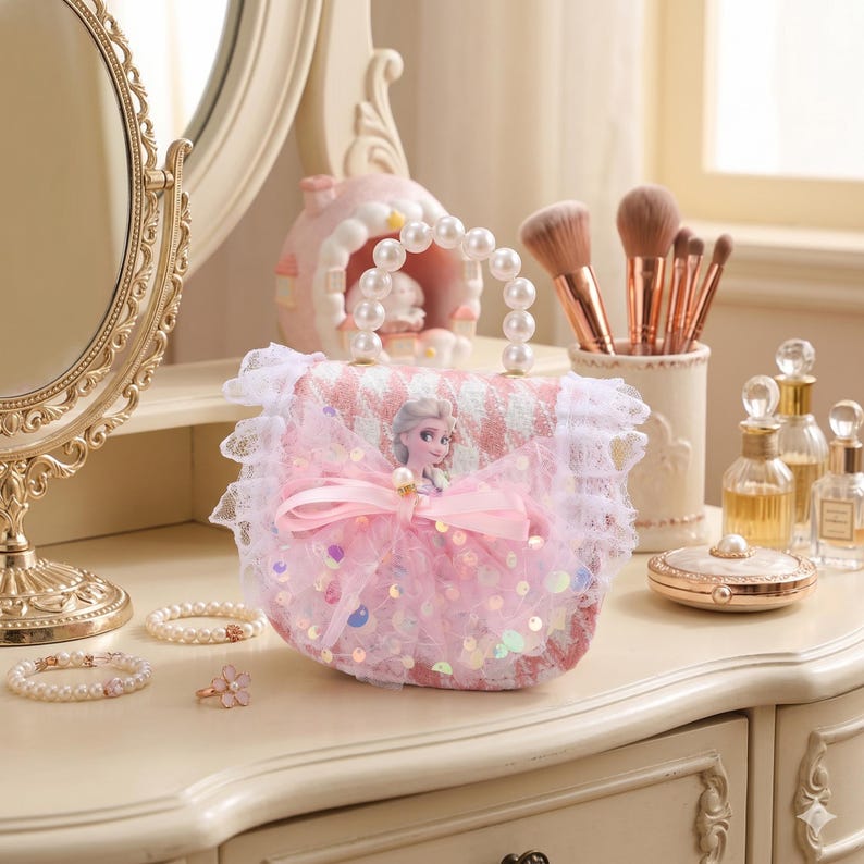 K&ouml;nnte beinhalten: Eine rosa-wei&szlig; gemusterte Handtasche mit Perlenhenkel und einem Prinzessinnenbild. Die Handtasche ist mit einer rosa Schleife und Pailletten verziert. Eine wei&szlig;e Spitzenborte umgibt die Handtasche.