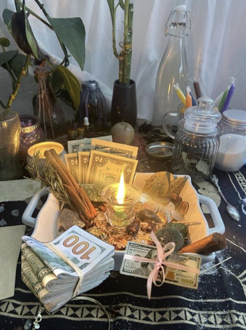 May include: A white square ceramic dish containing a lit green candle, cinnamon sticks, assorted coins, and paper currency. A thick stack of one hundred dollar bills is secured with a rubber band, and a single bill is tied with a light pink ribbon.