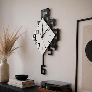 May include: A wall clock featuring a white diamond-shaped face with black hands and numerals 7 to 10. The clock is surrounded by a black frame with large, overlapping black numerals, and a black pendulum arm extending downwards with the number 6.