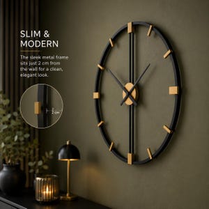 May include: A round wall clock with a black metal frame and gold-colored accents. The clock features thin black hands and gold markers. Text on the image reads: SLIM & MODERN. The sleek metal frame sits just 2 cm from the wall for a clean, elegant look.