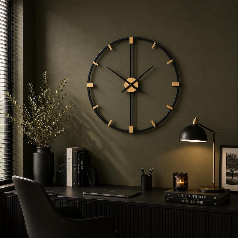 May include: A large circular wall clock featuring a thin black metal frame with gold-toned hour markers and central hands. The design includes vertical and horizontal crossbars that intersect at the center, creating a geometric open-face structure.