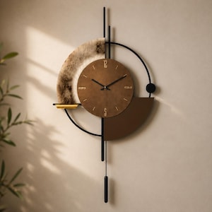 Op de afbeelding: Een wandklok met een centrale ronde bruine wijzerplaat met gouden cijfers op 12, 3, 6 en 9, omringd door een zwart metalen frame. Het bevat een gestructureerde houtnerf halve cirkel, een effen bruine halve cirkel en een verticaal pendel met gewicht.
