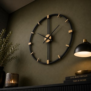 May include: A large circular wall clock featuring a thin black metal frame with gold-colored rectangular hour markers. The clock has two long vertical black bars intersecting at the center, where two black hands are attached to a gold circular hub.