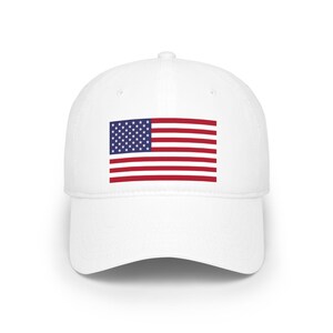 Könnte beinhalten: Eine weiße Baseballkappe mit der amerikanischen Flagge. Das Flaggenmuster zeigt ein blaues Rechteck mit weißen Sternen und rot-weißen Streifen. Die Kappe hat einen gebogenen Schirm und eine strukturierte Krone.