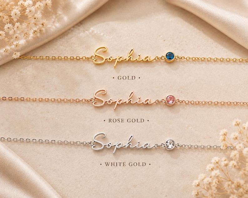 May include: Three delicate chain bracelets featuring the name Sophia in cursive script. The top bracelet is gold with a blue stone, the middle is rose gold with a pink stone, and the bottom is white gold with a clear stone. Text labels read Gold, Rose Gold, and White Gold.