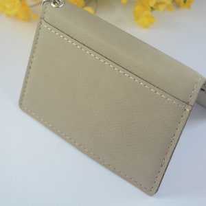 May include: A beige leather wallet with a stitched seam and a silver chain attached.