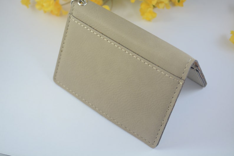 May include: A beige leather wallet with a stitched seam and a silver chain attached.