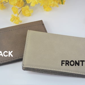 May include: A brown leather key chain with a silver key ring. The front of the key chain is beige leather with the word "FRONT" printed in black. The back of the key chain has the word "BACK" printed in white.