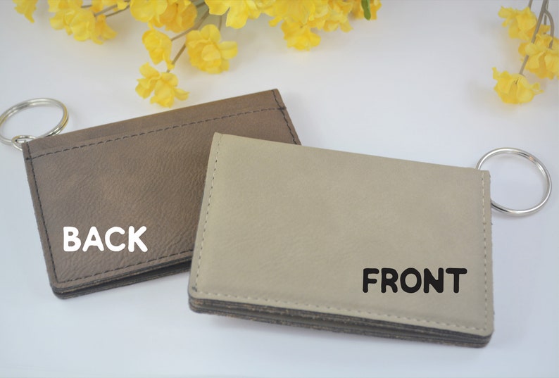 May include: A brown leather key chain with a silver key ring. The front of the key chain is beige leather with the word "FRONT" printed in black. The back of the key chain has the word "BACK" printed in white.