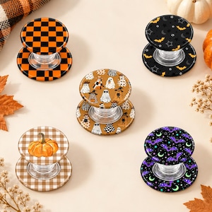 May include: Five circular phone grips with collapsible clear plastic bases. Designs include an orange and black checkerboard, a black background with yellow bats and stars, a tan background with various ghosts, a tan gingham with a pumpkin, and purple bats.