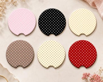 May include: A set of six circular car cup holder coasters, each featuring a white polka dot pattern. The coasters come in various colors including light pink, black, cream, brown, beige, and red, and each has a small notch at the bottom edge.