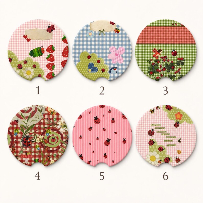 May include: Six circular car coasters featuring various patterns including ladybugs, strawberries, gingham checks, and floral motifs. Each coaster has a small notch at the bottom. Designs include pink, blue, red, and green color palettes with insects.