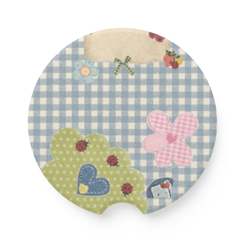 May include: A circular car coaster featuring a light blue and white gingham pattern. The design includes a beige rectangular label, a green scalloped shape with red ladybugs and a blue heart, a pink checkered flower, and small fruit motifs.