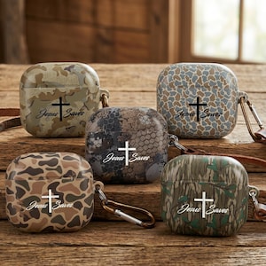 May include: Five camouflage-patterned earbud cases with the text "Jesus Saves" and a cross graphic. The cases feature various shades of green, brown, and tan, and include a metal carabiner clip for attachment.