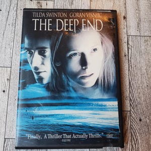 May include: DVD case for the movie "The Deep End" starring Tilda Swinton and Goran Visnjic. The case features a blue and white image of the actors and the ocean. The text on the case reads "Finally, A Thriller That Actually Thrills." - Esquire
