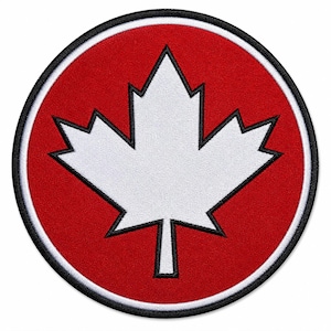 May include: A circular patch featuring a white maple leaf emblem on a red background. The leaf is outlined in black, and the patch has a black border. This patch is likely a symbol of Canadian identity.