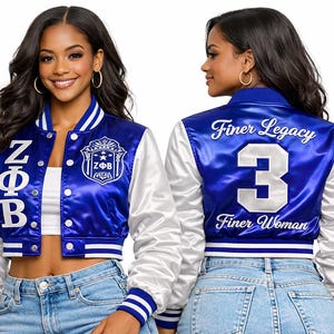 May include: A royal blue and white satin varsity jacket featuring the Greek letters ZΦB vertically on the front right, a ZΦB crest on the front left, and the text Finer Legacy, the number 3, and Finer Woman embroidered on the back.