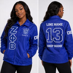 May include: A royal blue jacket with white lettering and a button-up front. The front features the Greek letters ZΦB and a crest. The back displays the number 13, the words "LINE NAME" and "SHIP NAME".