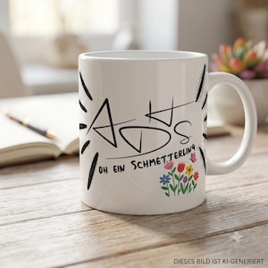 May include: A white ceramic mug featuring black stylized text that reads "ADS" and "OH EIN SCHMETTERLING" with a small graphic of colorful flowers and a butterfly. The mug has a curved handle and a smooth finish, displaying a clean, simple design.