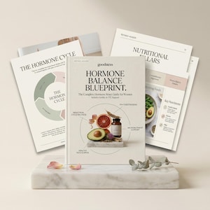 May include: A book titled "Hormone Balance Blueprint" with the text "The Complete Hormone Reset Guide for Women." The cover features illustrations of an avocado, grapefruit, and a supplement bottle. Several pages with diagrams and text are visible.
