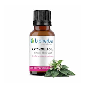 Op de afbeelding: Een bruine glazen fles patchouli-olie met een zwarte dop, met het label "bioherba aromatherapy PATCHOULI OIL." Het label bevat ook tekst in een andere taal. Een takje groene bladeren en witte bloemen staat naast de fles. Het label vermeldt "100% PURE ESSENTIAL OIL."