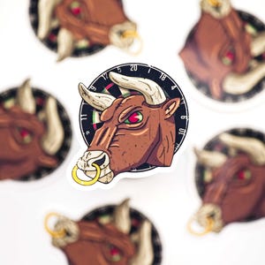 Op de afbeelding: Een verzameling stickers met een bruine stier met een gouden neusring en witte hoorns. De stier staat tegen een dartbord achtergrond. De stier heeft een boze uitdrukking met rode en groene ogen. De stickers staan op een witte achtergrond.