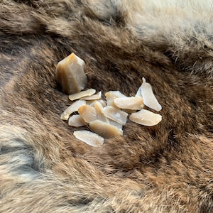 May include: A selection of raw, pale yellow-beige crystals and crystal shards. The crystals are scattered on a brown and tan fur-like surface. One crystal is a small, pointed tower.