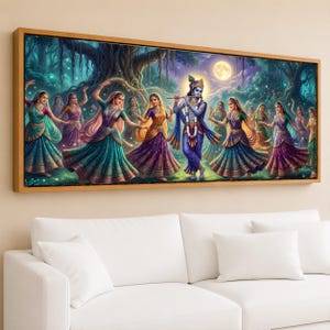 May include: A framed artwork depicting a vibrant scene of Indian dancers and a musician playing a flute. The artwork features a full moon, lush foliage, and figures in colorful traditional attire. The frame is a warm, natural wood tone.