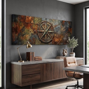 May include: A long rectangular wall art piece featuring a large, weathered, metallic compass rose centered over a textured, abstract background of deep rust, brown, and dark blue tones with visible map-like lines and distressed paint effects.