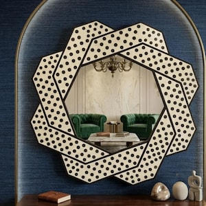 May include: A wall mirror featuring a complex, overlapping geometric frame with a cream-coloured surface and a repeating pattern of small black polka dots. The mirror has a central hexagonal reflective glass panel that shows a room interior.