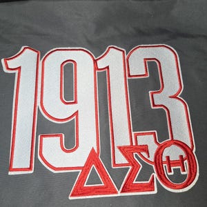 May include: Embroidered patch with the year "1913" in white with red trim. Below the numbers are the Greek letters Delta, Sigma, and Theta, also in red. A red circle with the letters "H" and "Θ" is on the right.