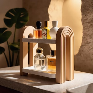 May include: A two-tiered beige shelf with an arched frame design holding five glass perfume bottles. The top shelf displays three bottles, while the bottom shelf holds two rectangular glass bottles, one of which is labelled with the text BOSS.