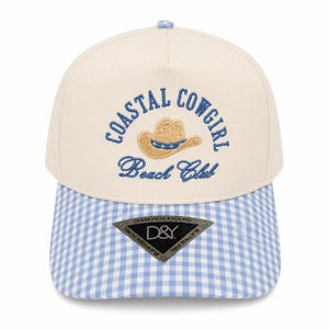 May include: Cream-colored baseball cap with a blue and white gingham brim. The cap features the embroidered text "COASTAL COWGIRL Beach Club" above a cowboy hat graphic. A small tag at the bottom reads "DIAMONDS & YOUNG".