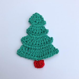May include: A crocheted Christmas tree ornament in teal green with a red pom-pom at the bottom.