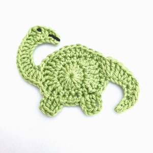 May include: A green crocheted dinosaur applique with black eyes.