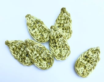 May include: Six handmade crochet leaf appliques in shades of green and cream. The leaves are oval-shaped with a textured, open weave design. They are scattered on a white background, showcasing their intricate details and color variations.