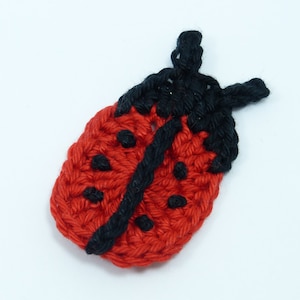 May include: A handmade crochet ladybug applique. The ladybug is primarily red with black accents, including the head, spots, and a line down the center. The craft item is made with a textured yarn, and is set against a white background.