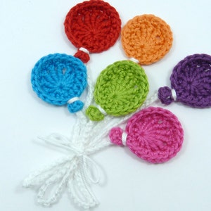 May include: A collection of six crocheted balloons in red, orange, blue, green, purple, and pink. Each round balloon has a white string attached, knotted at the base. The balloons are handmade.