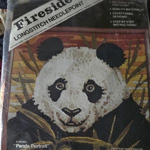May include: A Fireside Longstitch Needlepoint kit featuring a panda portrait design. The kit includes the materials to create a needlepoint piece that fits a 16" x 16" frame without a mat or a 20" x 20" frame with a mat. The kit is designed by Ron Smith.