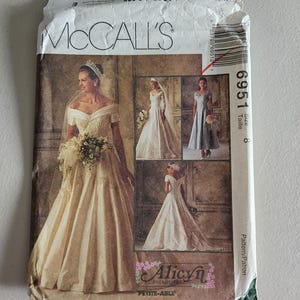 May include: A McCall's sewing pattern envelope featuring images of wedding dresses. The envelope is white with the McCall's logo and the pattern number 6951. The size is 8. The envelope also features the Alicyn Petite-Able logo.