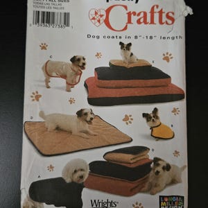 May include: Simplicity Crafts pattern for dog coats, sizes A, all sizes. The pattern includes dog coats in 8"-18" lengths. The image shows examples of dog coats and dog beds. The pattern is from Wrights and Longia Miller Design.