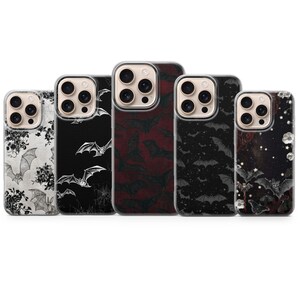 May include: Five phone cases with bat-themed designs. The cases feature black, white, and burgundy colours. Some cases have floral accents, while others showcase bat silhouettes and spiderwebs.