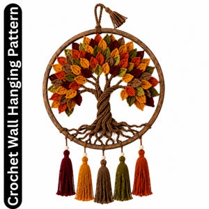 Op de afbeelding: Gehaakt wandkleedpatroon met een boomontwerp met kleurrijke bladeren in rood, oranje en groen. De boom staat in een houten hoepel, met een gevlochten stam en wortels. Decoratieve kwasten in verschillende kleuren hangen eronder.